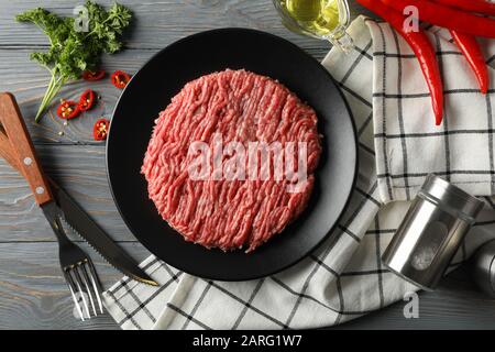 Gewürze und Teller mit Hackfleisch auf Holzgrund, Draufsicht Stockfoto