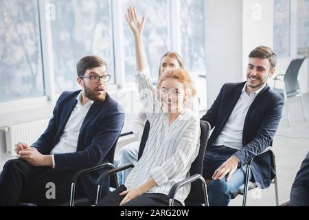 Eine selbstbewusste Geschäftsfrau, die die Hand aufhebt, um beim Seminar Fragen zu stellen