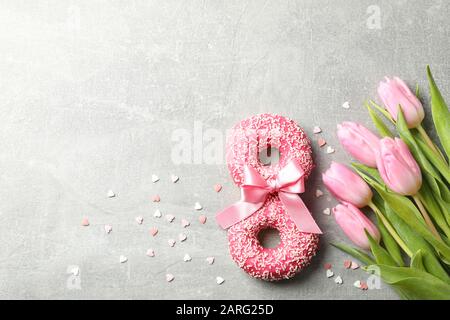 8 aus Donuts und pinken Tulpen auf grauem Hintergrund, Platz für Text Stockfoto