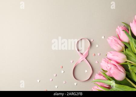 Pinke Tulpen, Süßigkeiten in Herzform und 8 auf grauem Hintergrund, Platz für Text Stockfoto