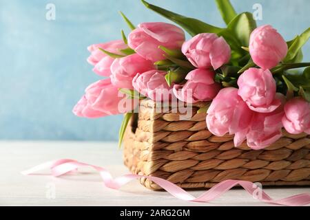 Korb mit Tulpen vor blauem Hintergrund, Nahaufnahme Stockfoto