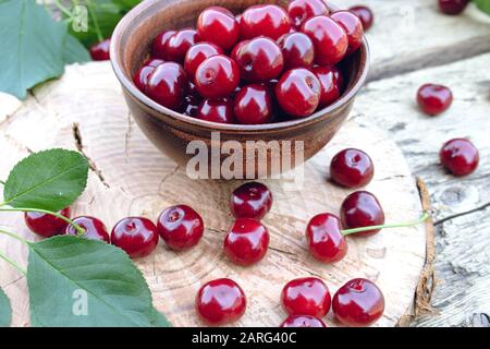 Rote Kirsche auf alten Holztafeln verstreut. Saftiges, köstliches Obst. Nahaufnahme. Stockfoto