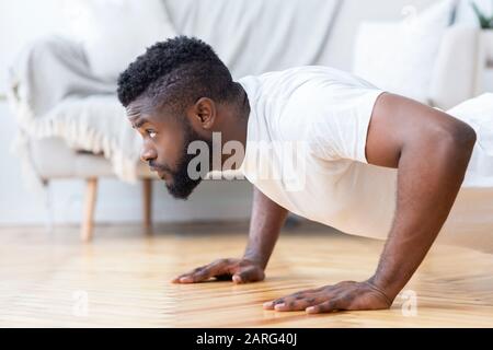 Junger schwarzer Mann, der Push-ups macht, Seitenansicht Stockfoto