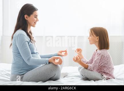 Mutter und kleine Tochter erwarten, dass sie zusammen Yoga machen Stockfoto