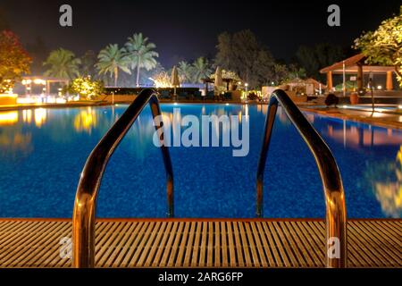 Blick auf den tropischen Pool, umgeben von Palmen und Sesseln Stockfoto