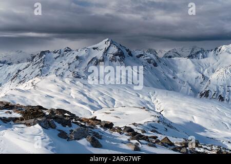 Blick vom Gipfel der La Masse im französischen Ferienort Les Menuires über die alpen. Eine Wolkenbank sitzt über den fernen Gipfeln. Stockfoto