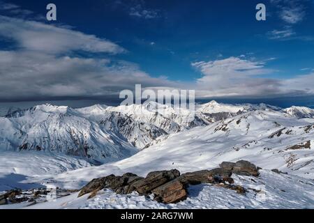 Blick vom Gipfel der La Masse im französischen Ferienort Les Menuires über die alpen. Eine Wolkenbank sitzt über den fernen Gipfeln. Stockfoto