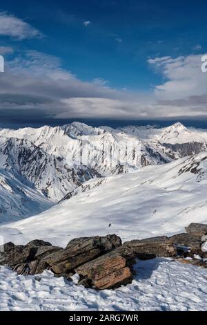 Blick vom Gipfel der La Masse im französischen Ferienort Les Menuires über die alpen. Eine Wolkenbank sitzt über den fernen Gipfeln. Stockfoto