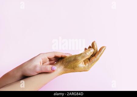 Perfekte Maniküre mit modischer Nagelkunst und Hand mit goldenem Glitter auf pinkfarbenem Hintergrund mit Kopierraum. Stockfoto