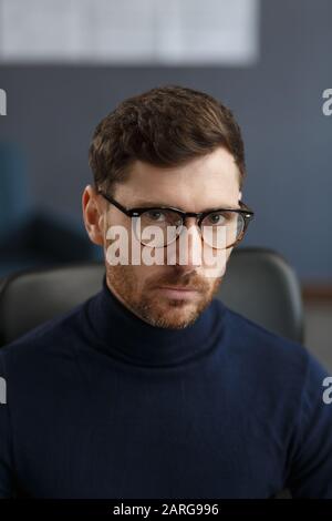 Junger Geschäftsmann im Amt. Business-Porträt eines hübschen bärtigen Mannes, der Brillen trägt, die am Arbeitsplatz sitzen. Selbstbewusster Geschäftsmann wurde Stockfoto