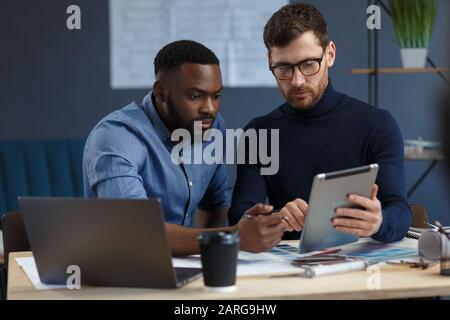 Multiracial Engineer Team, das mit Tablet-PC im Büro arbeitet. Architekten wählen Farben für das Gebäude mit Farbfeldern, Skizzen und Planung aus Stockfoto