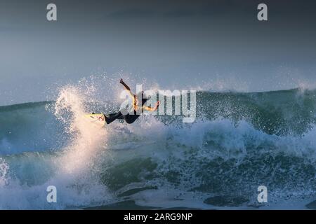 Spektakuläre Action, während ein junger Surfer eine große wilde Welle in Fistral in Newquay in Cornwall reitet. Stockfoto