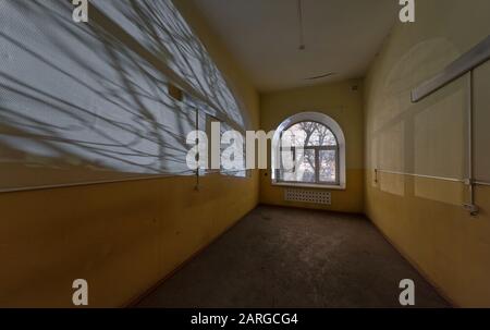 Nachts Schatten von den Ästen an der Wand des leeren Raums eines verlassenen Krankenhauses Stockfoto
