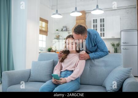 Vater und Tochter sehen sich den Bildschirm eines Smartphones an. Stockfoto