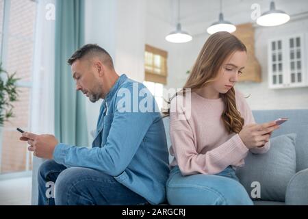 Vater und Tochter sitzen auf dem Rücken der Couch zueinander. Stockfoto
