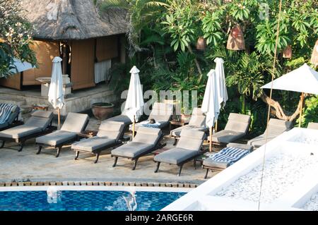 KUTA, Indonesien - 24. Juli: Leute sitzen am Strand von Kuta, Bali unter einer Kokospalme neben einigen Surf Boards am 24. Juli 2009 in Bali, Indonesien. Ba Stockfoto