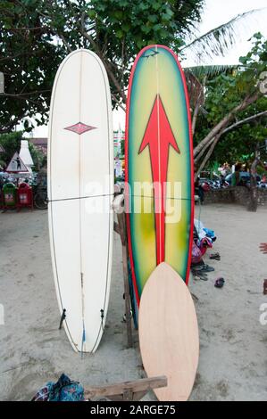 KUTA, Indonesien - 24. Juli: Leute sitzen am Strand von Kuta, Bali unter einer Kokospalme neben einigen Surf Boards am 24. Juli 2009 in Bali, Indonesien. Ba Stockfoto