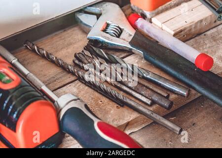 Auf dem Tisch liegen Werkzeuge für die Arbeit mit einem Schraubenschlüssel, einem Schraubendreher und einem Bohrer. Verschiedene Schreinwerkzeuge. Werkzeuge für den Job. Stockfoto