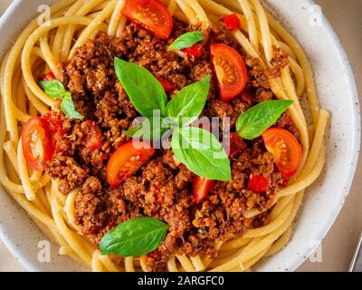Nudelbolognese mit Tomatensauce, gemahlenes Hackfleisch, Basilikumblätter auf dem Hintergrund Stockfoto