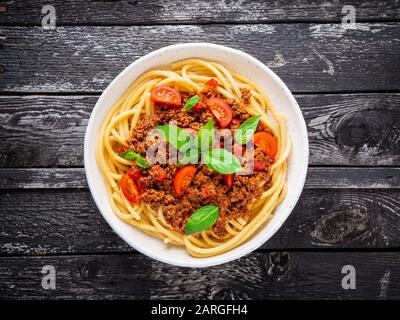 Nudelbolognese mit Tomatensauce, gemahlenes Hackfleisch, Basilikumblätter auf dem Hintergrund Stockfoto