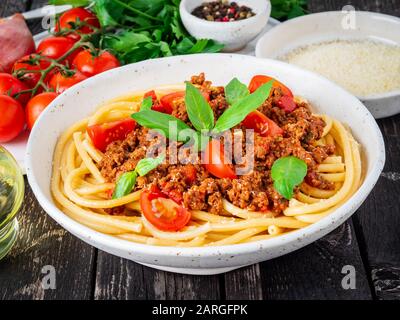 Nudelbolognese mit Tomatensauce, gemahlenes Hackfleisch, Basilikumblätter auf dem Hintergrund Stockfoto