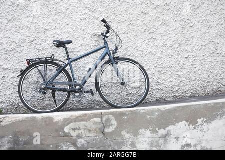 Dunkelgraue Fahrradständer lehnen sich mit rauer Oberfläche an die weiß verputzte Wand Stockfoto