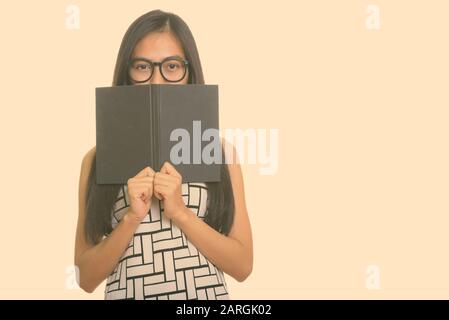 Jungen asiatischen Teenager nerd Mädchen hinter Buch ausblenden Stockfoto