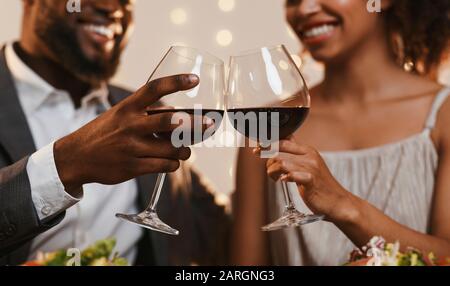 Nahaufnahme des afrikanischen Ehepaares, das mit Rotwein töstet Stockfoto