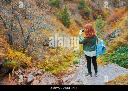 Weibliche Wanderer, die selfie im Bergwald einnehmen. Die Touristin mit Rucksack bewundert die Bergkulisse. Stockfoto