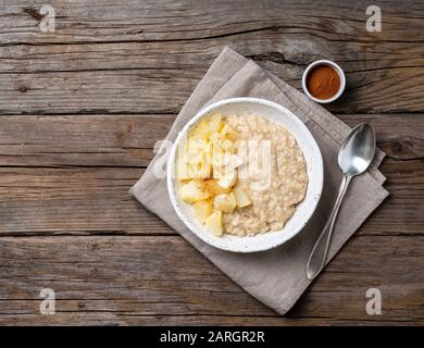 Große Schüssel mit leckerem und gesundem Haferbrei mit apfel zum Frühstück, Morgenmahlzeit. Blick auf den Gipfel, in der Nähe, rustikaler Holztisch Stockfoto