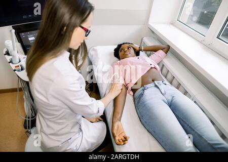 Ultraschall, Physiotherapie, Rehabilitationskonzept. Junge Frau Arzt Physiotherapeut Sonograph untersucht den Ellenbogen mit einem Ultraschall-Scan von ihr Stockfoto