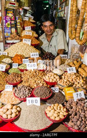 Ein Verkäufer verkauft in seinem Geschäft auf dem Gewürzmarkt in Alt-Delhi Nüsse und viele verschiedene Gewürze Stockfoto