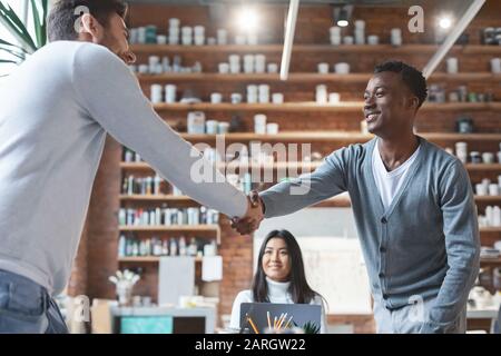 Junge Geschäftspartner schütteln während der Gruppenbesprechung die Hände Stockfoto
