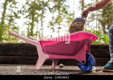 Kinder, die SAS in Plastikspielzeug mit Schubkarre draußen legen. Stockfoto