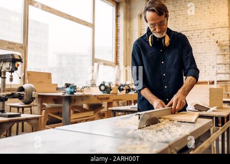 Männlich arbeitet im Zimmerei. Man-Einstellsäge Maschine. Stockfoto