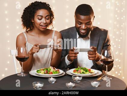 Junges Paar sitzt im Restaurant und fotografiert Lebensmittel Stockfoto