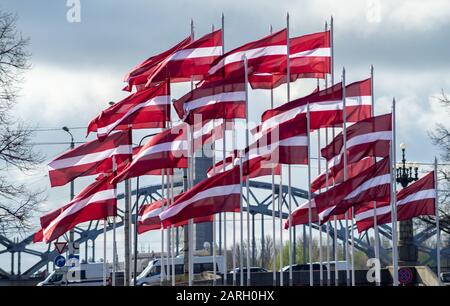 Viele weiße Flaggen von Bordeaux aus Lettland vor dem Hintergrund des trüben Himmels Stockfoto