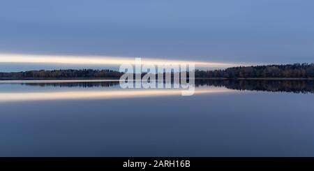 Ruhige Landschaft. Sonnenuntergang am See, ruhige Wasseroberfläche, symmetrische Reflexion. Stockfoto