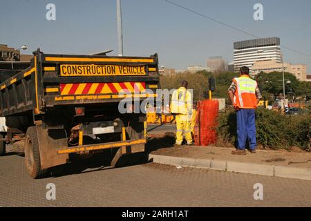 Baggerlader und Straßenarbeiter auf Straßenrändern, Braamfontein, Johannesburg, Gauteng, Südafrika. Stockfoto