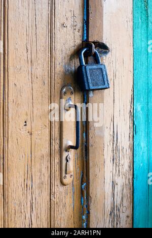 Alte geschlossene Tür mit Vorhängeschloss und Knopf, vertikaler Schuss Stockfoto