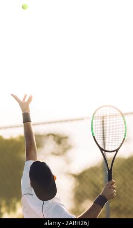Junger Mann wirft einen Tennisball zum Aufschlag. Tennisspieler, der den Ball in einem Spiel serviert. Stockfoto