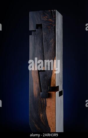 Holzskulptur von Abdollah Nafisi. Verebnete Holzschnitte in Abschnitten. Saß auf einer schwarzen Sockelplatte mit einem blauen Leuchten dahinter. Stockfoto
