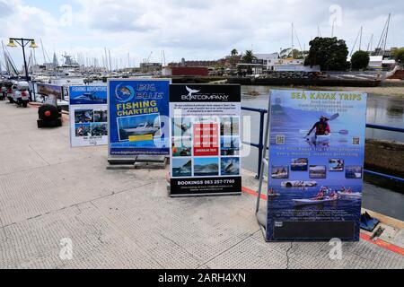 Werbetafeln für Touristenattraktionen entlang der Promenade in Simon's Town, Kapstadt, Südafrika. Stockfoto