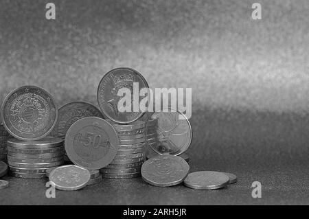 Münzstapel aus verschiedenen Nationen mit Euro und Cent vor silberfarbenem Hintergrund mit Kopierraum rechts Stockfoto