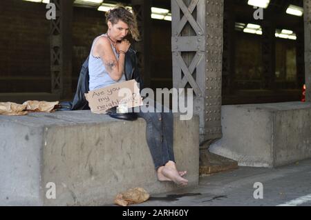 Alkoholsüchtige, obdachlose Frau, die um Geld bettelt und ein Zeichen hält - sind Sie mein Nachbar? Stockfoto