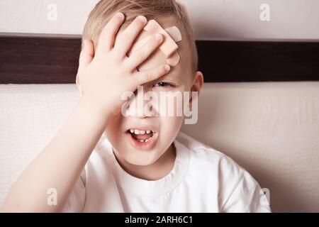 Kleiner Junge mit Putz am Kopf, fühlt sich nicht gut an und stöhnt vor Schmerzen Stockfoto