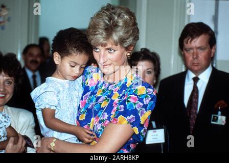 HRH Prinzessin Diana hält ein Kind, das während eines Besuchs in einem Waisenhaus in Sao Paulo, Brasilien, mit HIV-AIDS betroffen ist (hinten rechts Ken Wharfe persönliche Protektion Stockfoto