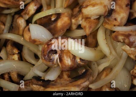 Sautieren Champignons und Zwiebeln in einer Pfanne mit Öl, Gewürze, und Dampf Stockfoto