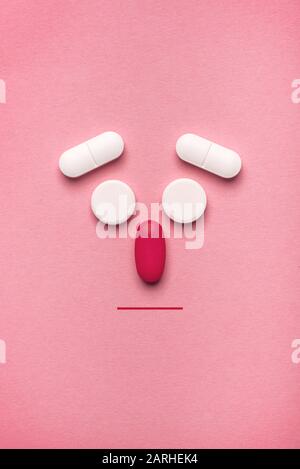 Stilisiertes, krankes Gesicht Emoticon aus Pillen und Tabletten, flaches Layout mit Blick auf den oberen Rand und Kopierbereich Stockfoto