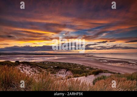 Sonnenuntergang über der Budle Bay mit Blick auf Lindisfarne in der Nähe von Bamburgh, Northumberland, England, Großbritannien Stockfoto